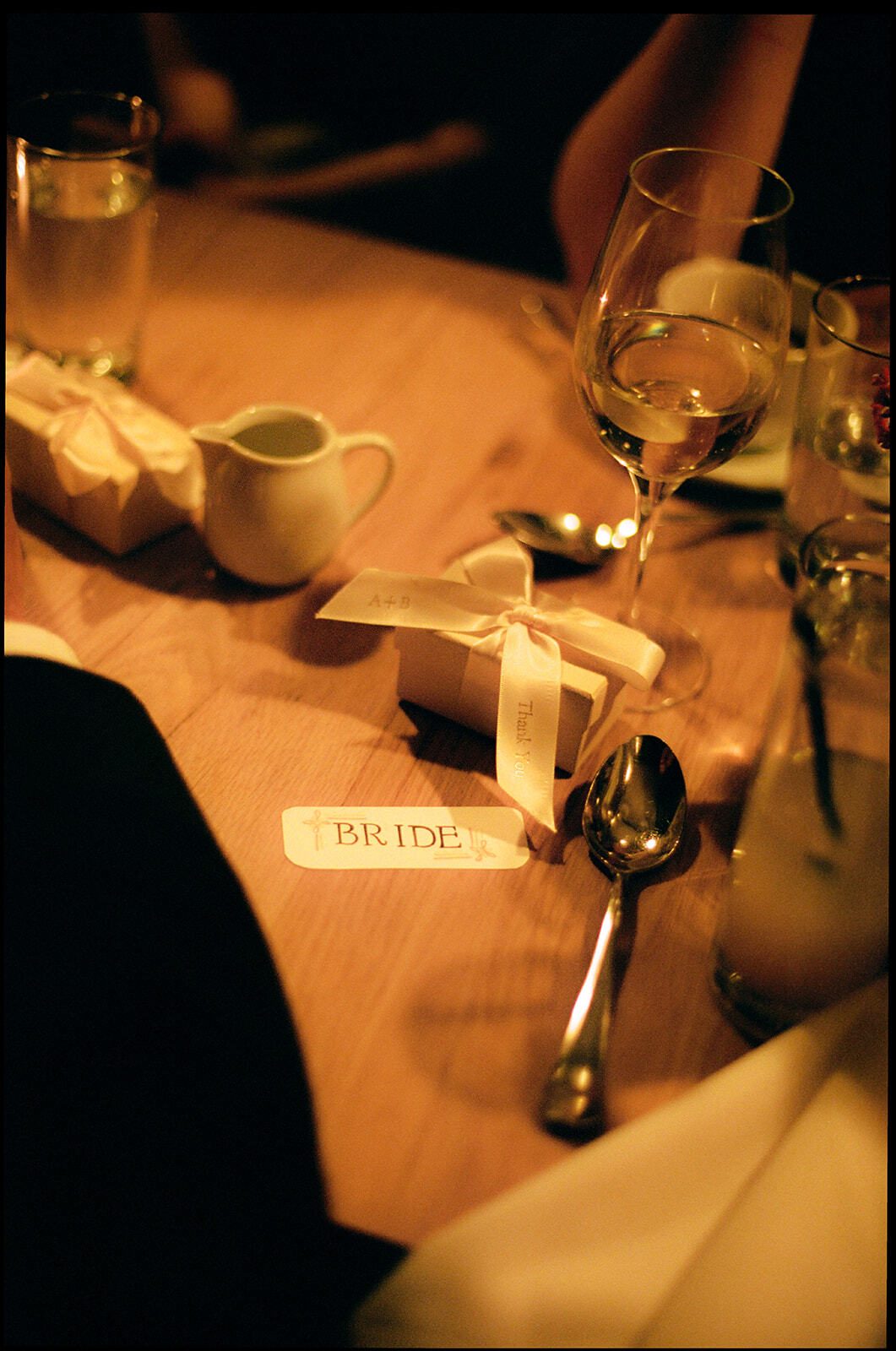 Wedding table detail with place card, champagne glasses and warm candlelight at Adena and Brian's wedding, by Brooklyn wedding photographer Lana Dubkova on film.